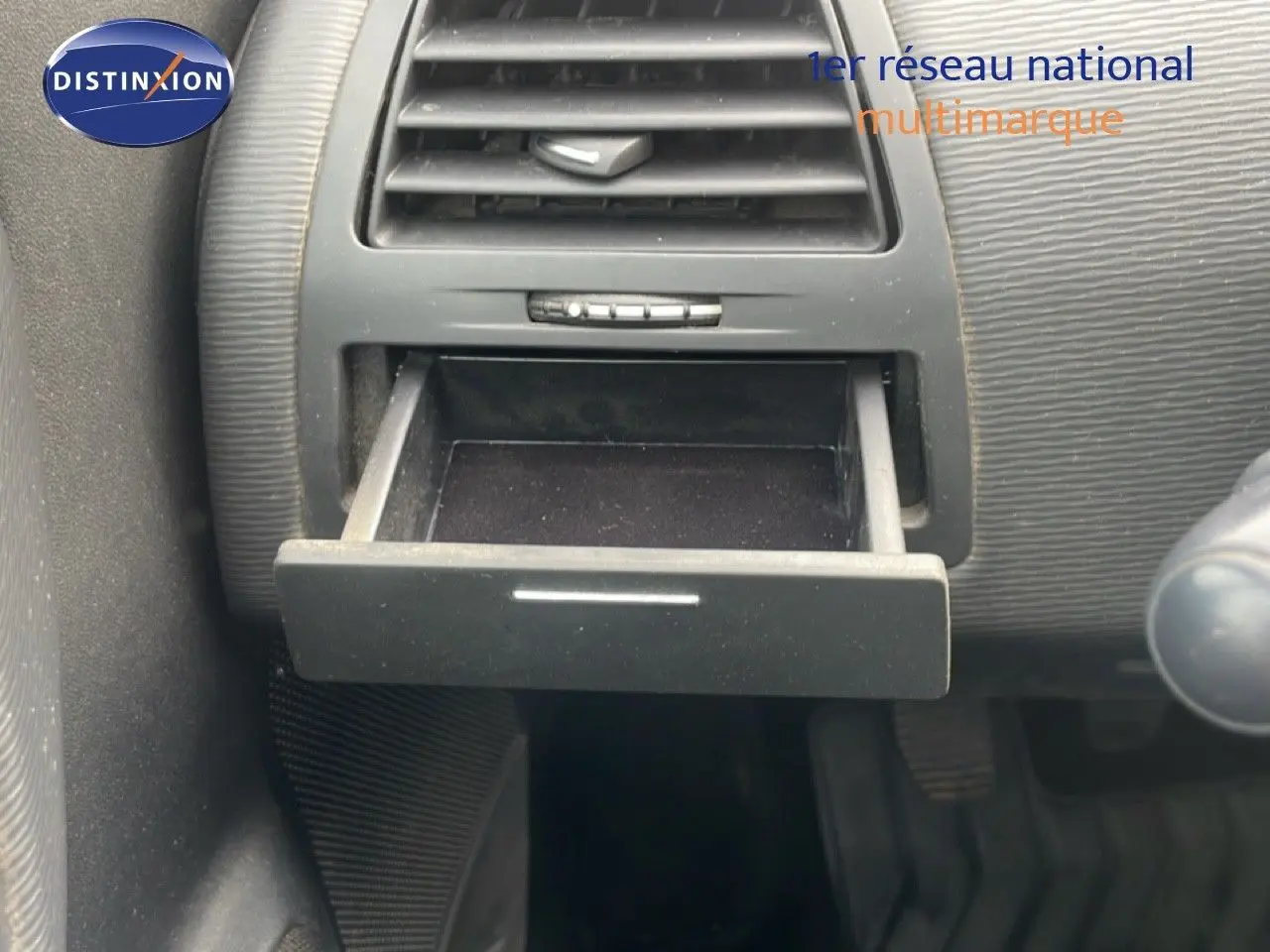 Gros plan sur la boîte à gants ouverte du tableau de bord d'une Citroën C4 noire métal de 2009.