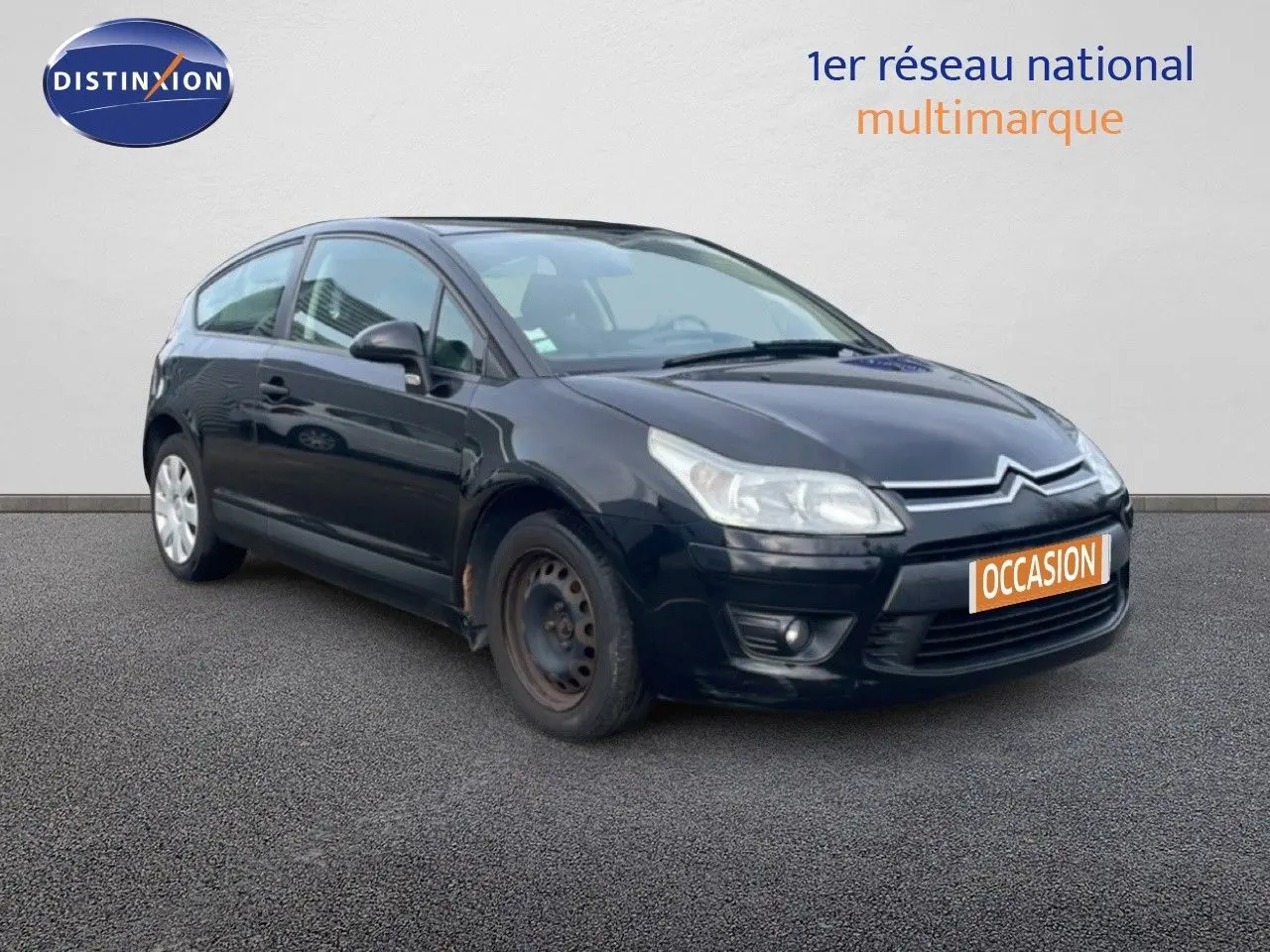 Citroën C4 Coupé noir métal vue 3/4 avant droit, avec jante acier avant visible et plaque occasion orange.
