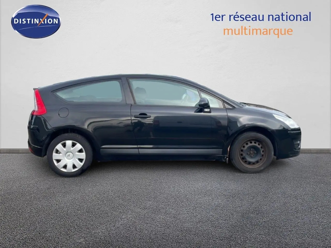 Profil côté gauche d'une Citroën C4 Coupé 2009 noire métal avec deux roues différentes visibles sur sol gris.