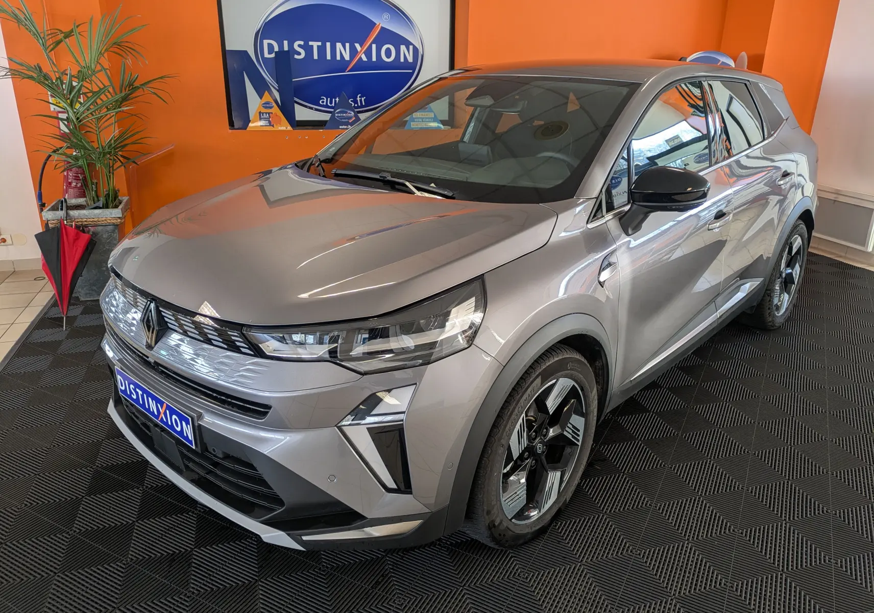 Renault Symbioz gris cassiopée métal en 3/4 avant droit, avec calandre lumineuse et jantes bi-ton distinctives.