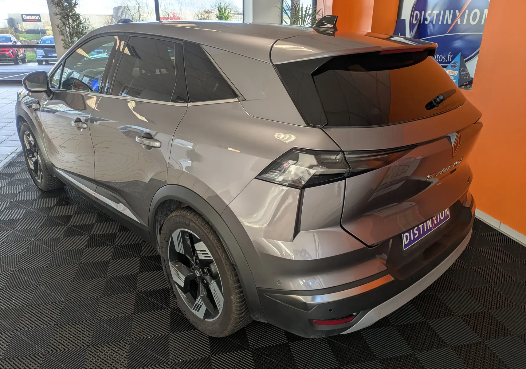 Vue 3/4 arrière droite du Renault Symbioz gris cassiopée métallisé avec vitres teintées et jantes noires.