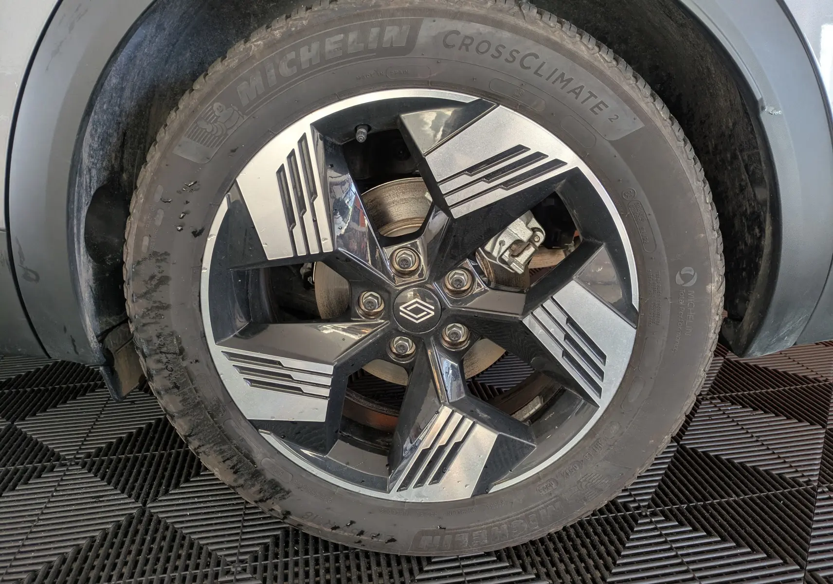 Gros plan sur la roue avant droite du Renault Symbioz gris Cassiopée, jante alliage bicolore au design géométrique.