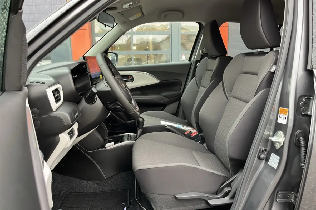 Vue intérieure côté gauche de la Suzuki Swift 2026 gris minéral, montrant les sièges tissu et le tableau de bord moderne.