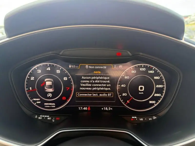 Vue rapprochée du tableau de bord numérique noir de l'Audi TT Coupé 2016 avec affichage des compteurs et message d'alerte Bluetooth.