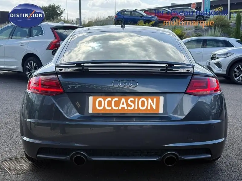 Vue arrière d'une Audi TT Coupé gris foncé avec becquet et double sortie d'échappement chromée.