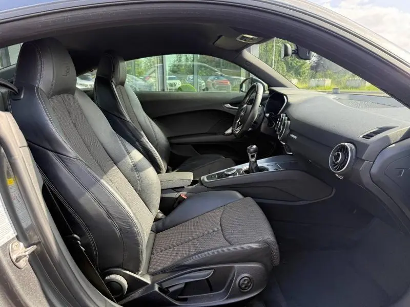 Intérieur noir de l'Audi TT Coupé 2016 vu côté conducteur, avec sièges sport en cuir et volant multifonction.