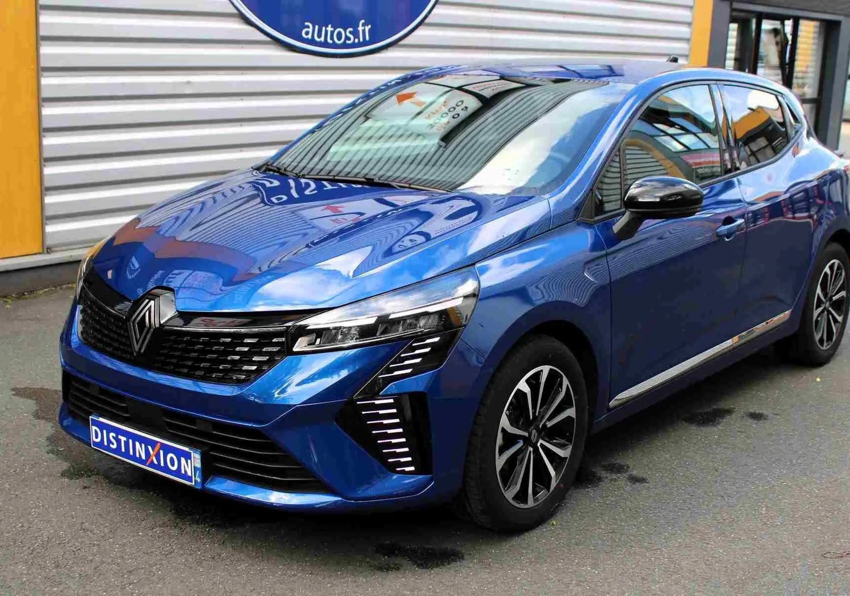 Renault Clio hybride bleu Iron Metal vue 3/4 avant droit, avec calandre noire et feux LED en forme de C.