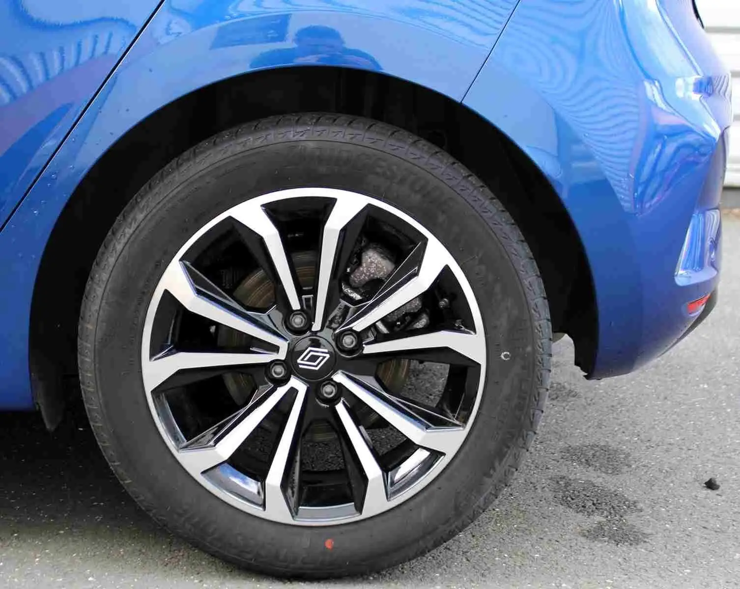 Gros plan sur la roue avant droite d'une Renault Clio bleu iron metal avec jante alliage noire et argentée.