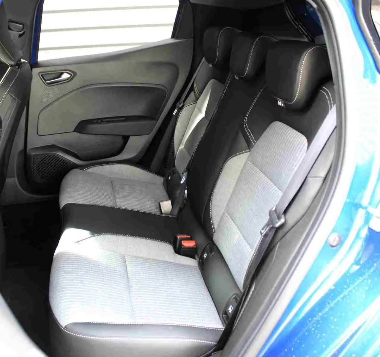 Vue intérieure côté arrière droit de la Renault Clio bleu Iron Metal, montrant les sièges arrière bi-matière gris clair et noir.