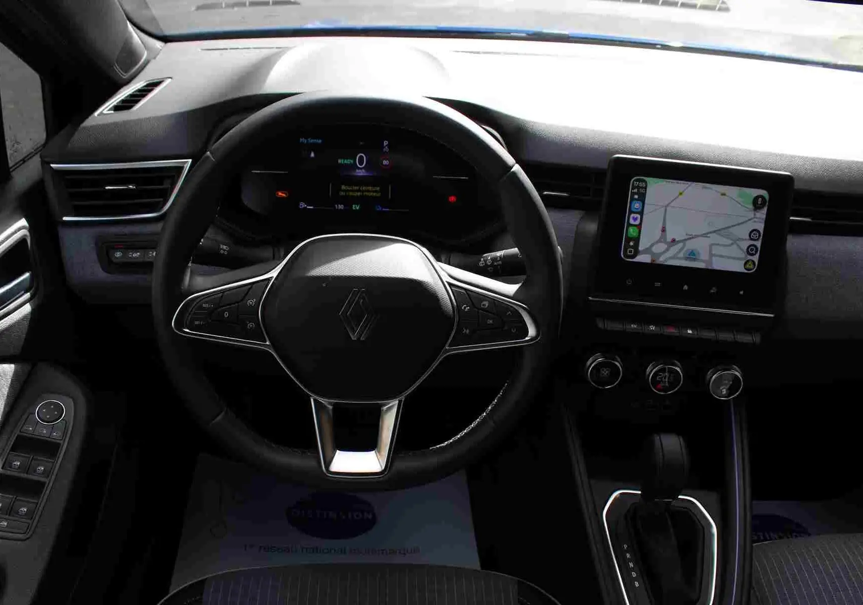 Vue intérieure centrée sur le volant et tableau de bord de la Renault Clio hybride 2025 avec écran tactile et commandes au volant.