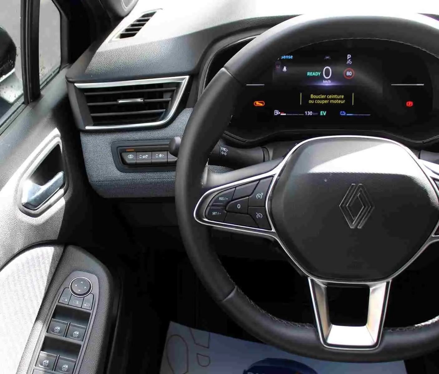 Vue intérieure centrée sur le volant noir de la Renault Clio 2025 avec tableau de bord numérique et commandes au volant.