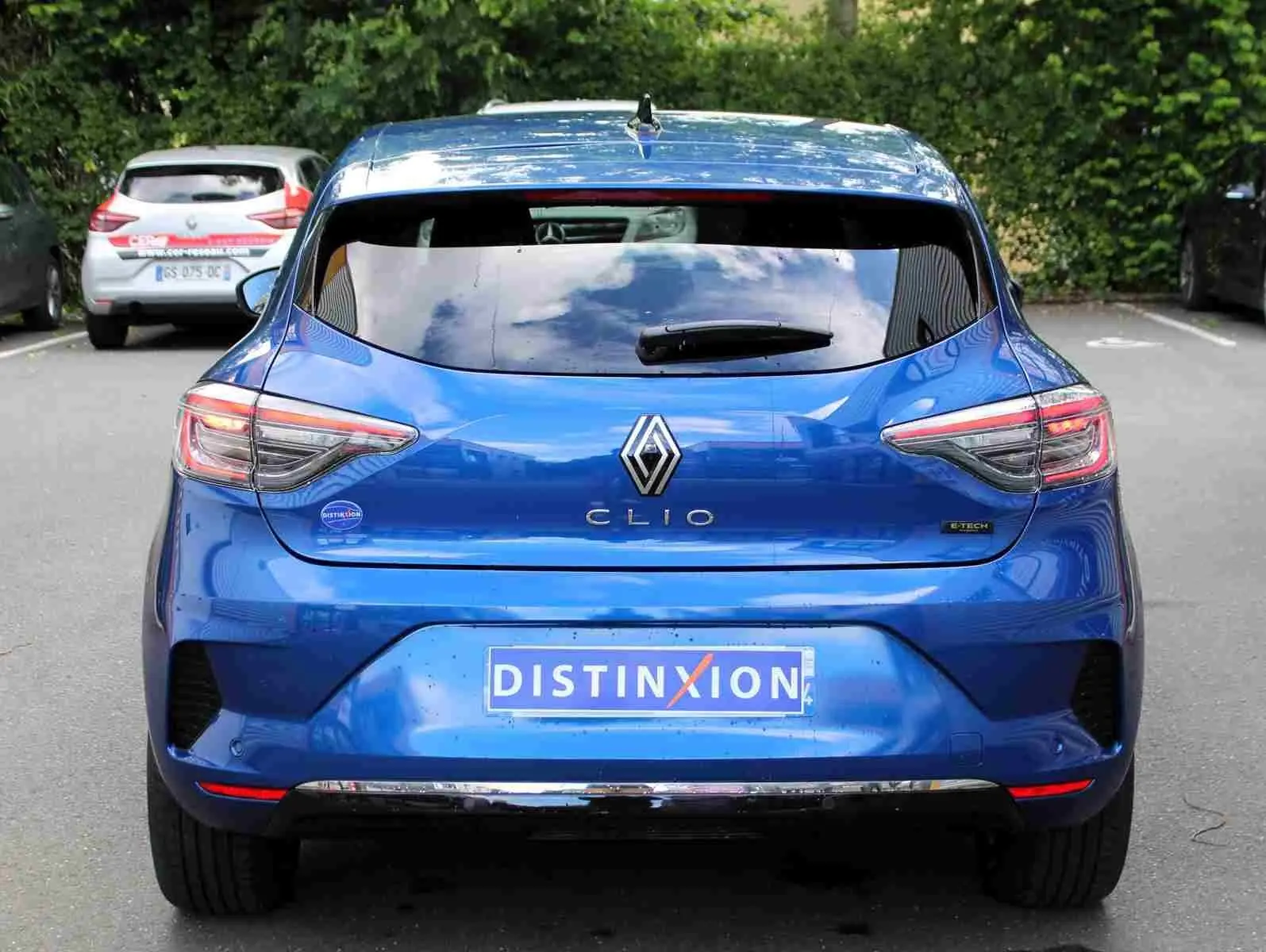 Vue arrière d'une Renault Clio bleu iron metal 2025 avec logo distinctif et plaque d'immatriculation Distinxion.
