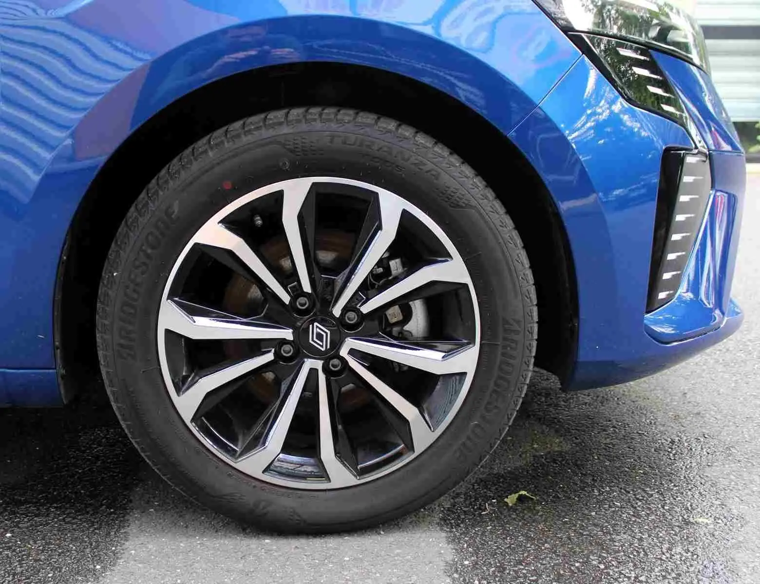 Gros plan sur la roue avant droite de la Renault Clio bleu iron metal avec jante alliage au design moderne.