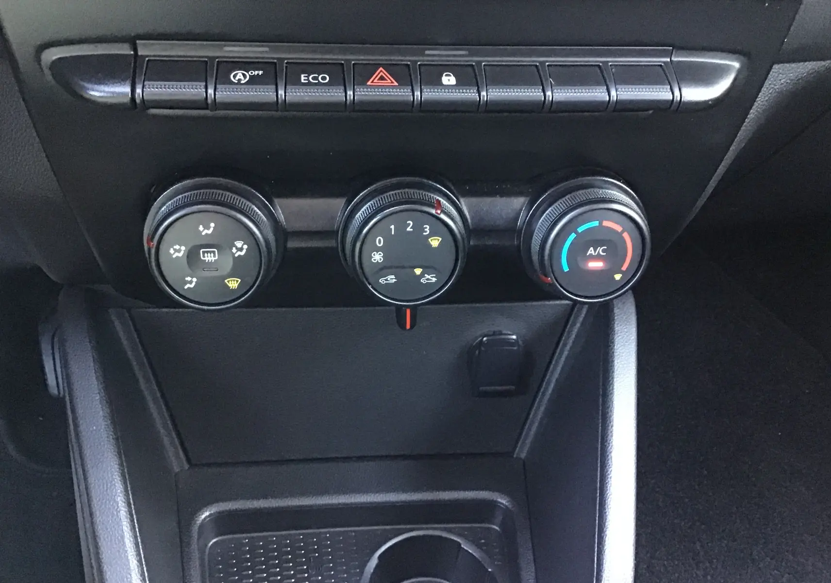 Vue rapprochée des commandes de climatisation et boutons fonctionnels du tableau de bord du Dacia Duster 2021.