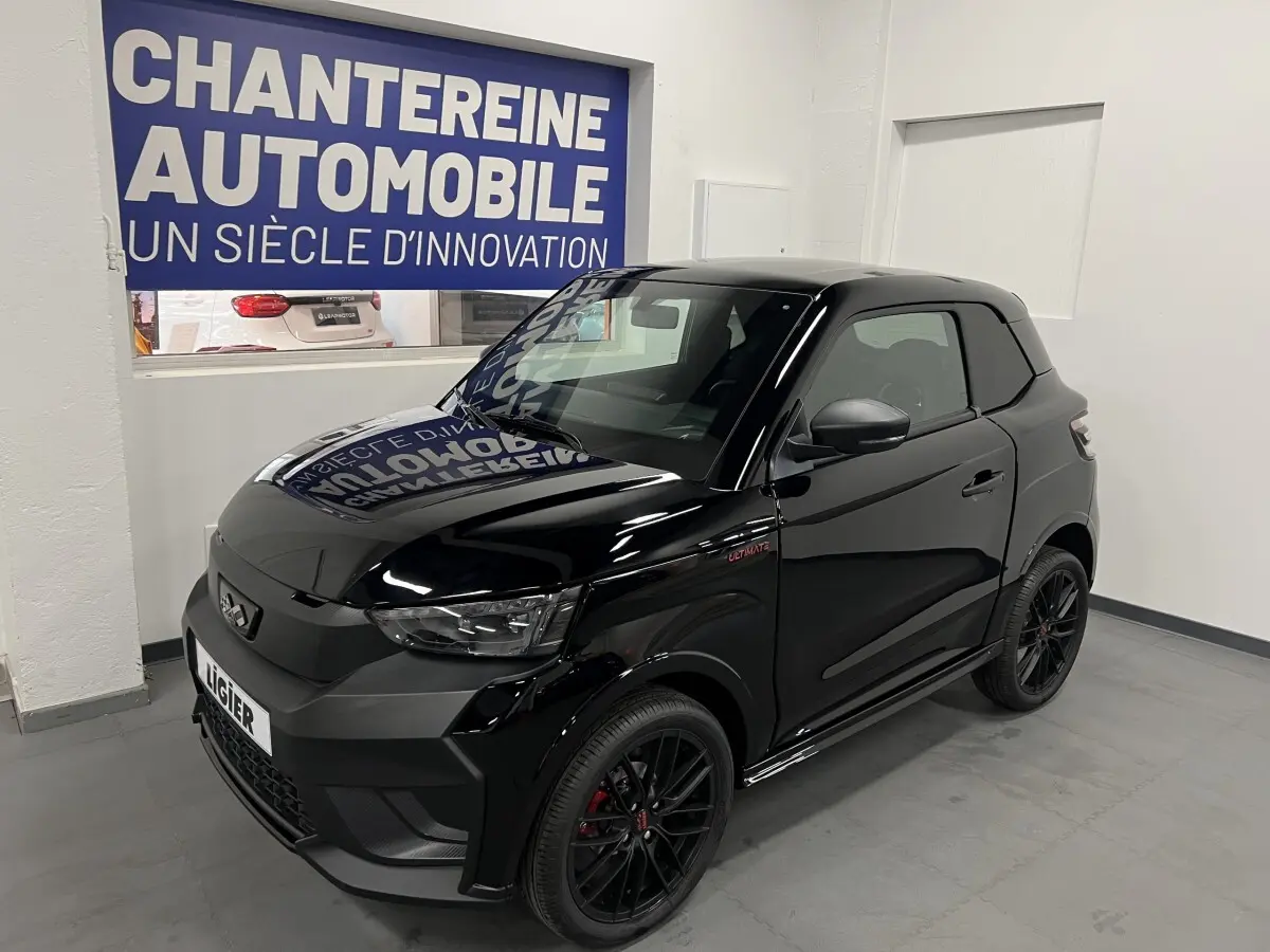 Vue 3/4 avant d'une Ligier JS50 noire mate avec jantes alu noires et badge Ultimate visible sur l'aile avant droite.