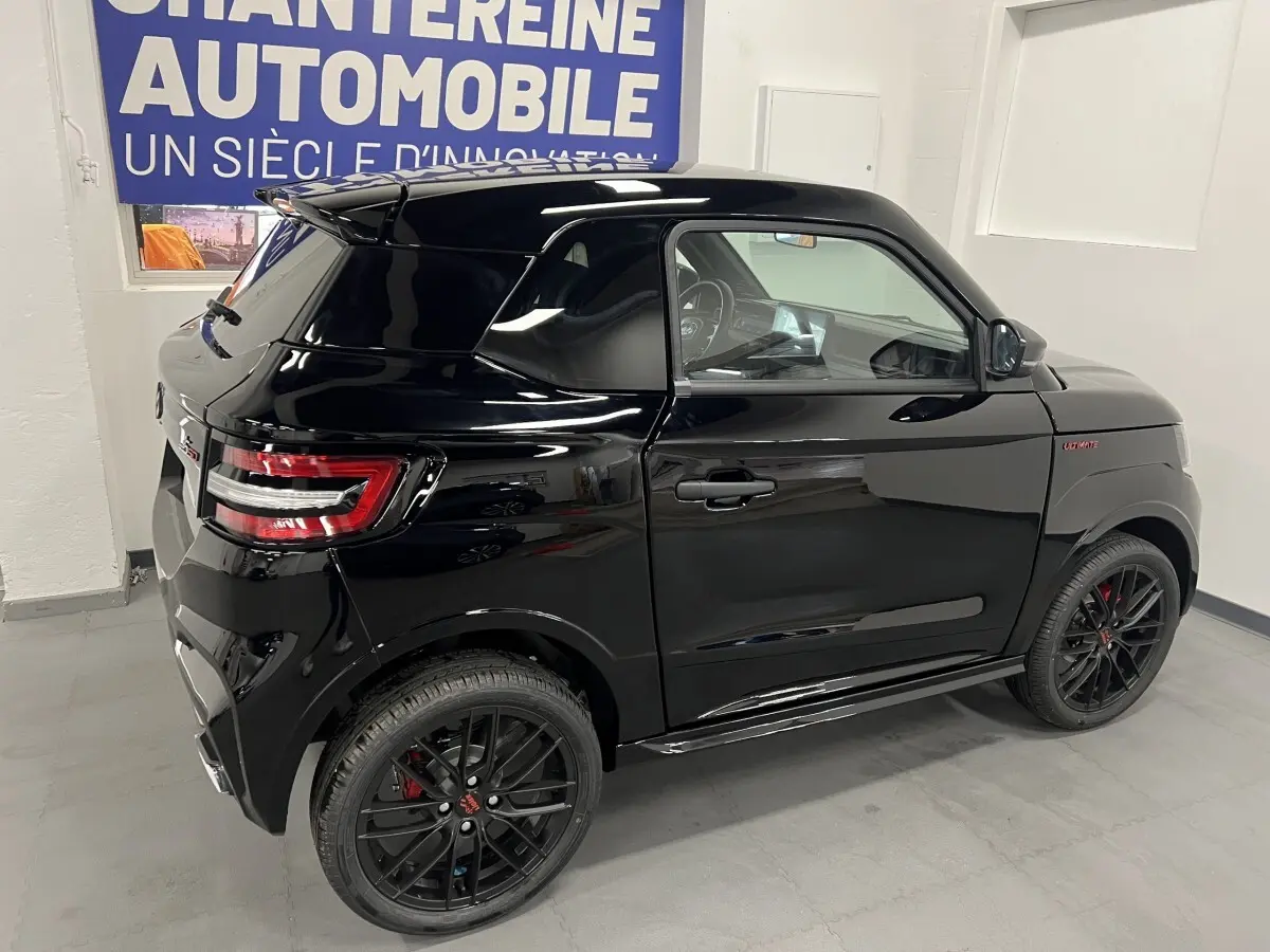 Vue 3/4 arrière droite d'une Ligier JS50 noire mate avec jantes alu noires 16 pouces et logo Ultimate rouge sur aile avant.
