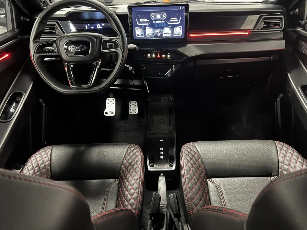 Vue intérieure avant du tableau de bord noir de la Ligier JS50 Ultimate avec écran tactile et sièges cuir surpiqués rouges.