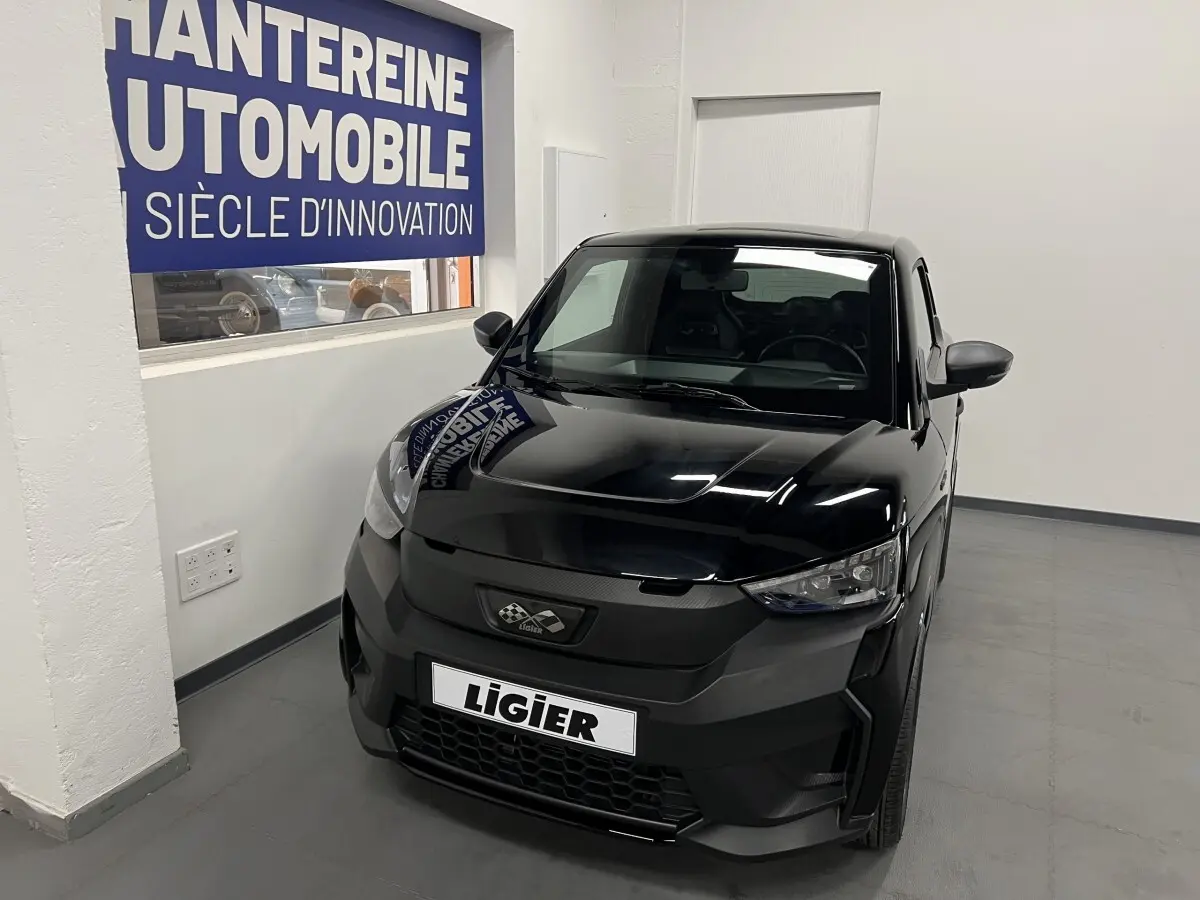 Vue 3/4 avant d'une Ligier JS50 noire 2026 avec calandre noire mate et phares LED dans un showroom.