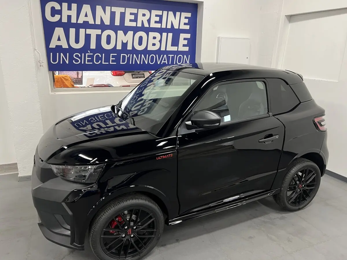 Vue 3/4 avant droite d'une LIGIER JS50 noire mate avec jantes alu noires et badge Ultimate sur l'aile avant.