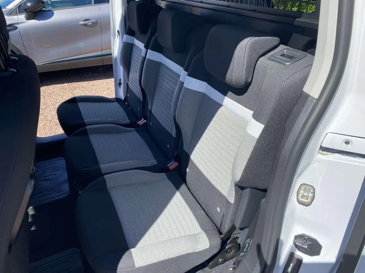 Vue intérieure côté droit sur la banquette arrière grise et noire du Citroën Berlingo blanc 2025 avec porte coulissante ouverte.