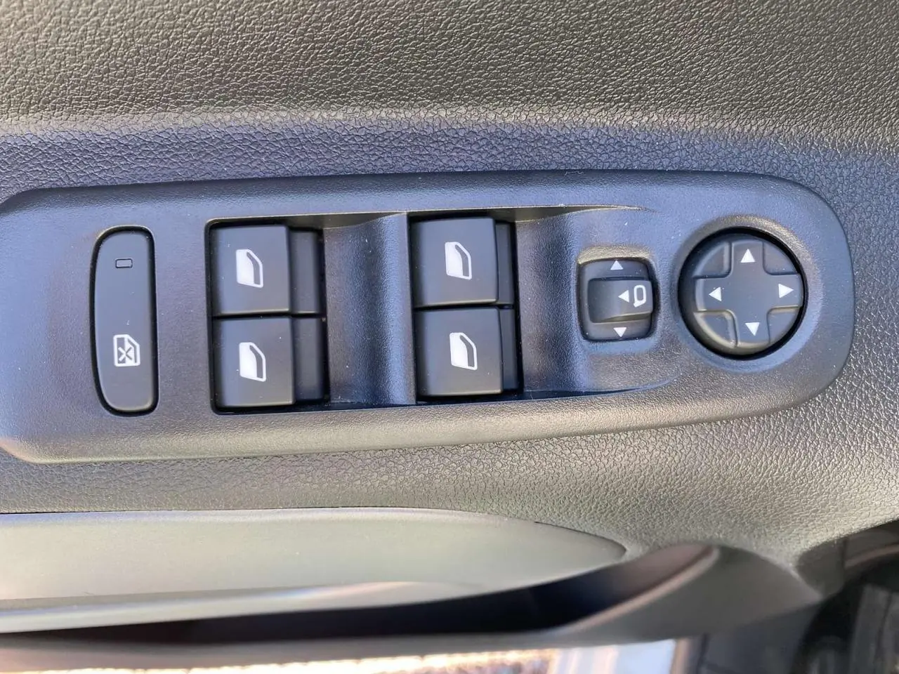 Gros plan sur les commandes des vitres électriques et réglages des rétroviseurs côté conducteur du Citroën Berlingo blanc 2025.