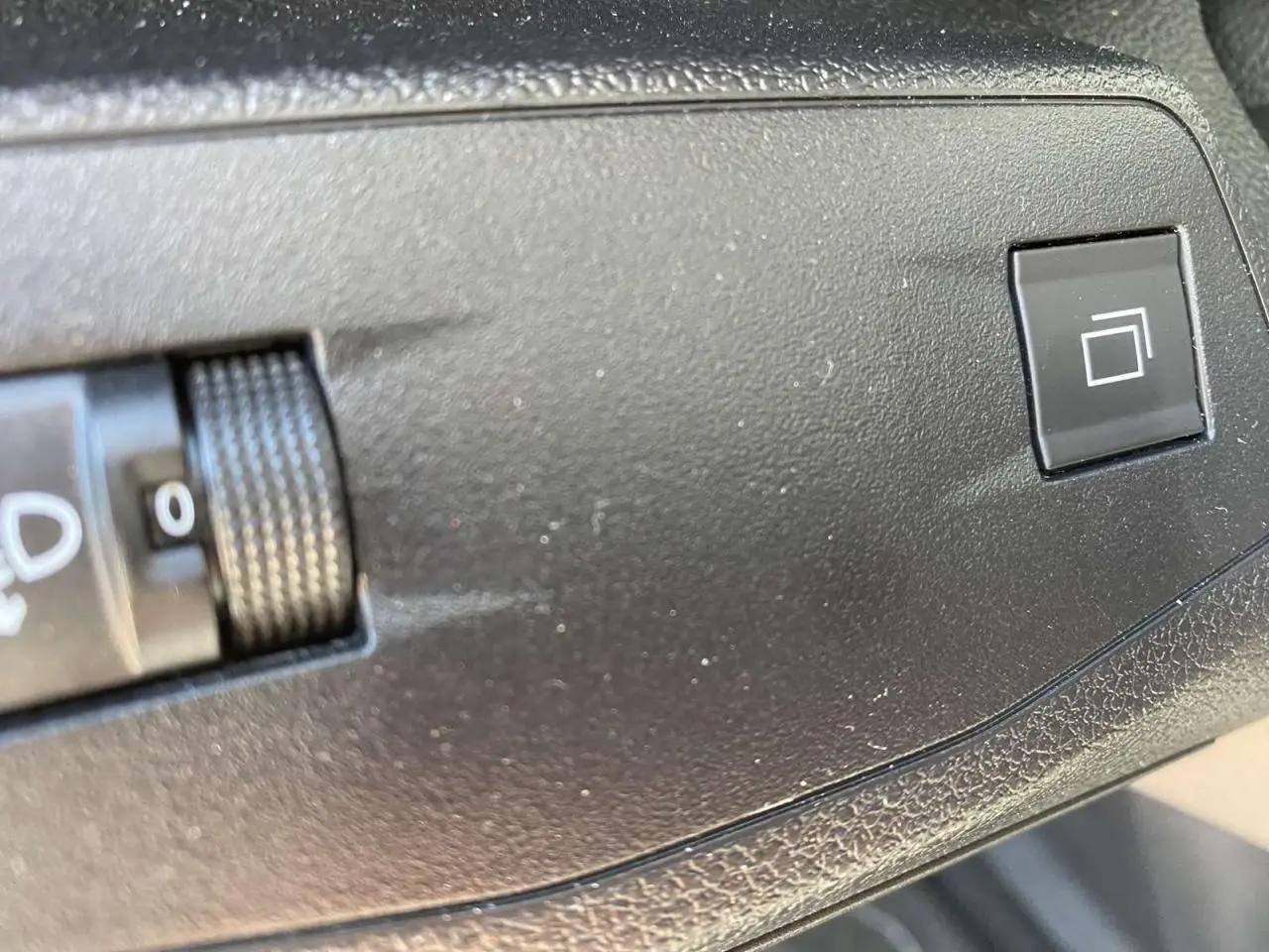 Gros plan sur le bouton de réglage des phares et la commande de l'écran tactile dans l'habitacle du Citroën Berlingo blanc 2025.