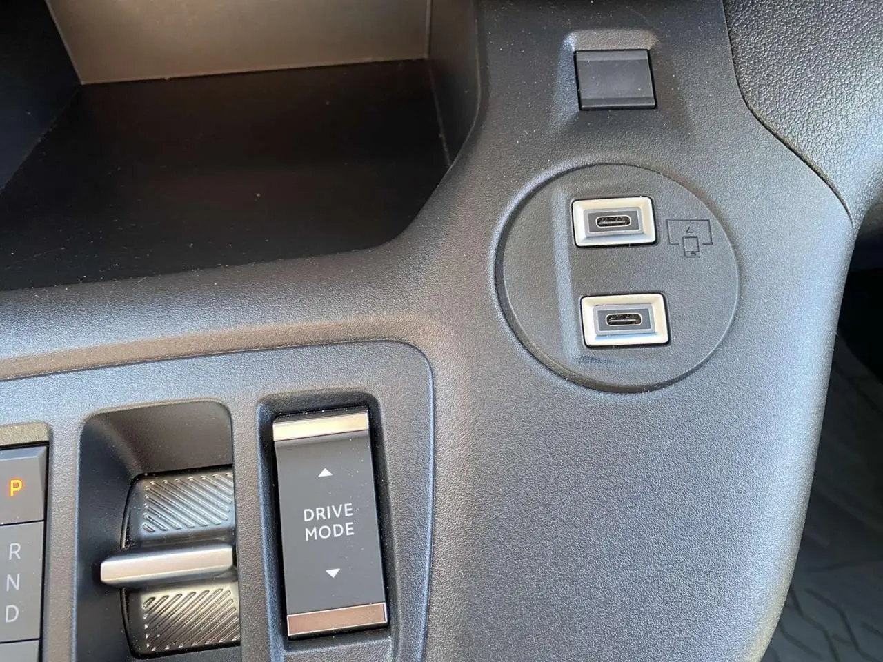 Gros plan sur la console centrale noire du Citroën Berlingo 2025 avec boutons Drive Mode et deux ports USB-C.
