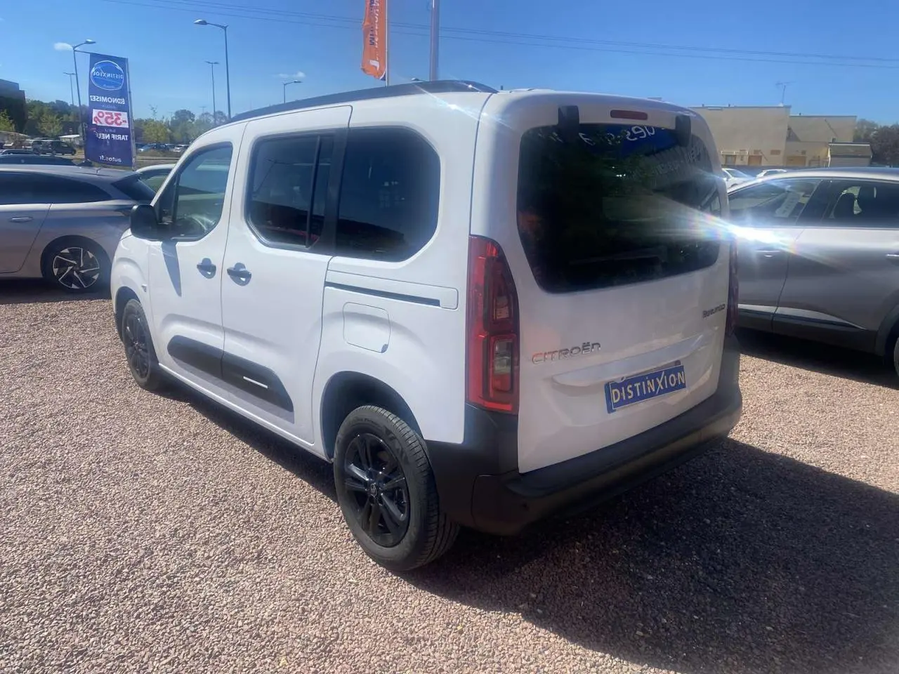 Vue 3/4 arrière droite du Citroën Berlingo blanc 2025 avec portes coulissantes et jantes noires sur parking.
