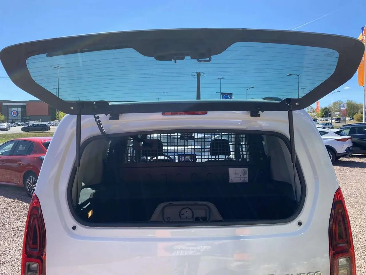 Vue arrière du Citroën Berlingo blanc 2025 avec hayon vitré ouvert et séparation intérieure visible.
