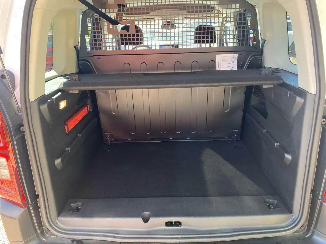 Vue arrière du coffre spacieux du Citroën Berlingo blanc 2025 avec séparation métallique et tablette amovible.