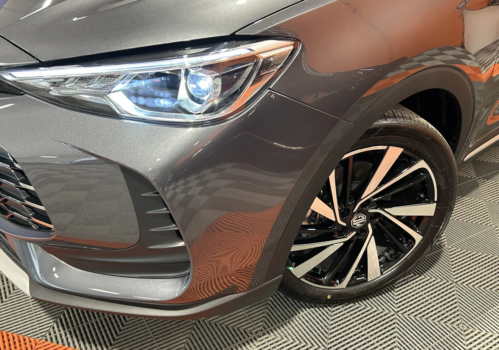 Gros plan sur l’avant droit du MG ZS Hybrid+ 197 Luxury gris Candem, mettant en valeur le phare LED et la jante alliage bicolore.