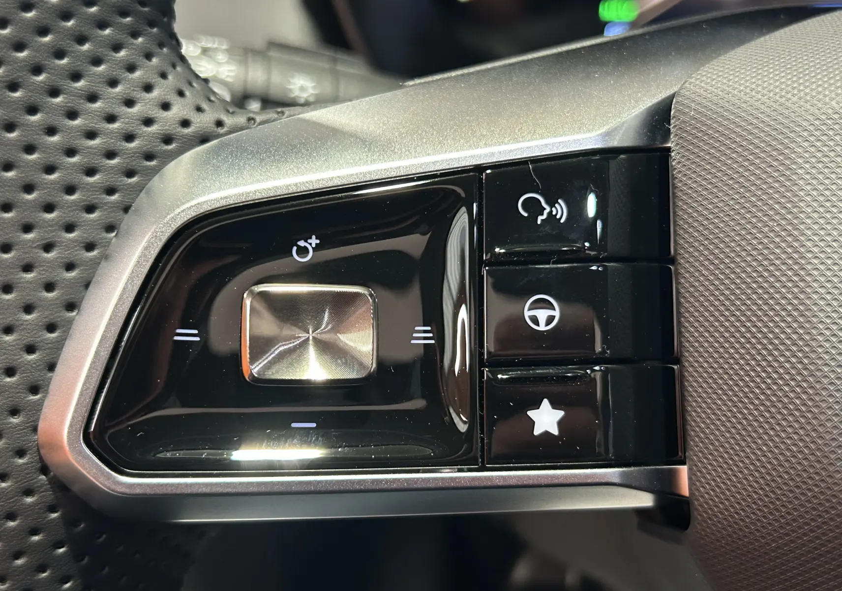 Gros plan sur les commandes noires et argentées au volant perforé du MG MOTOR ZS Hybrid+ 197 Luxury Candem Grey.