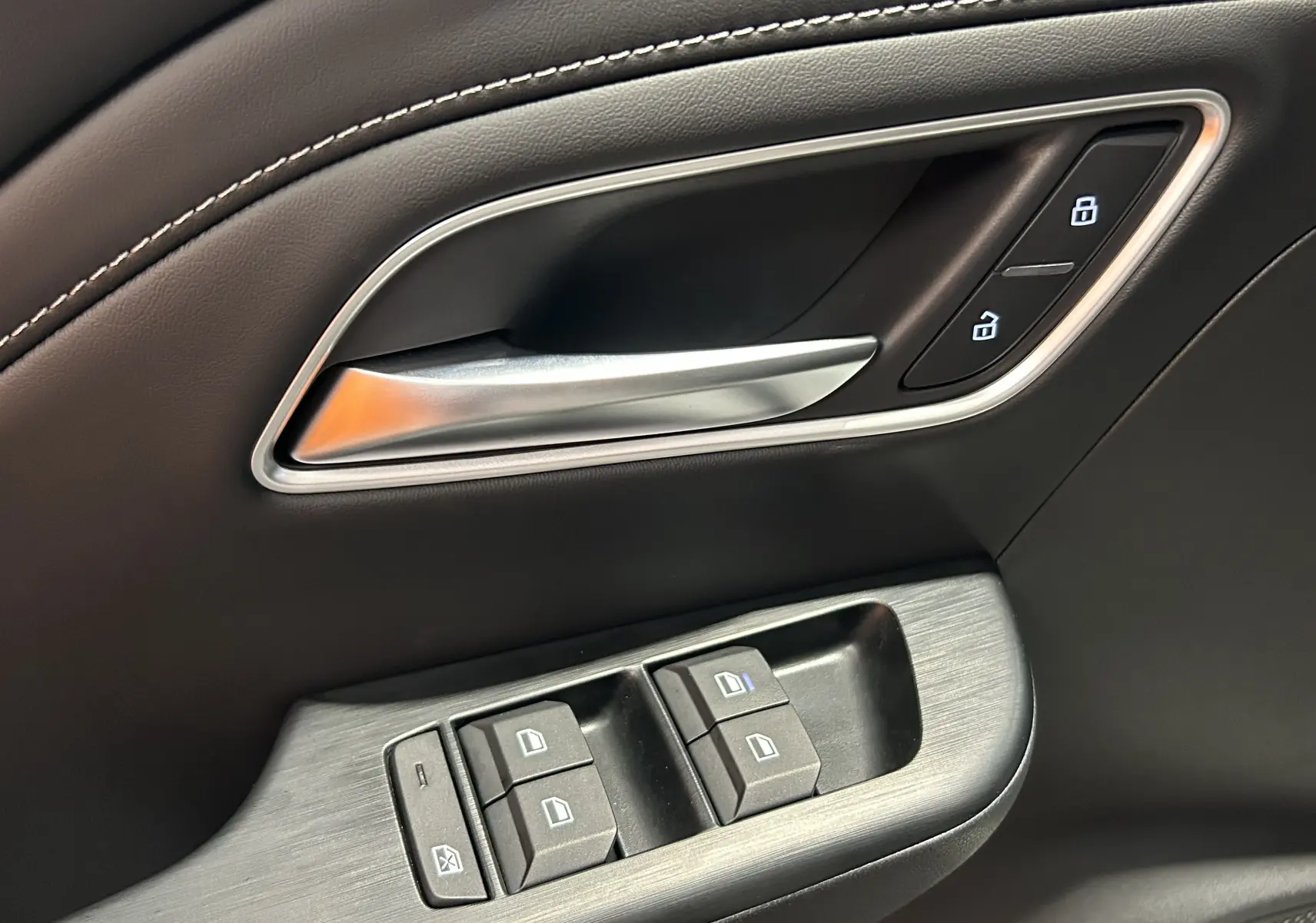 Gros plan sur la poignée intérieure et les commandes de fenêtre côté conducteur du MG Motor ZS Hybrid+ 2026 en cuir noir.
