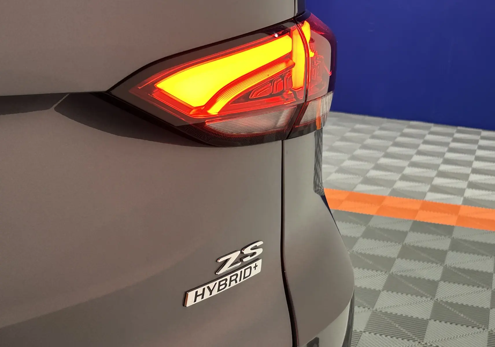Gros plan sur l'arrière droit gris Candem avec feu arrière allumé et badges ZS Hybrid+ visibles.
