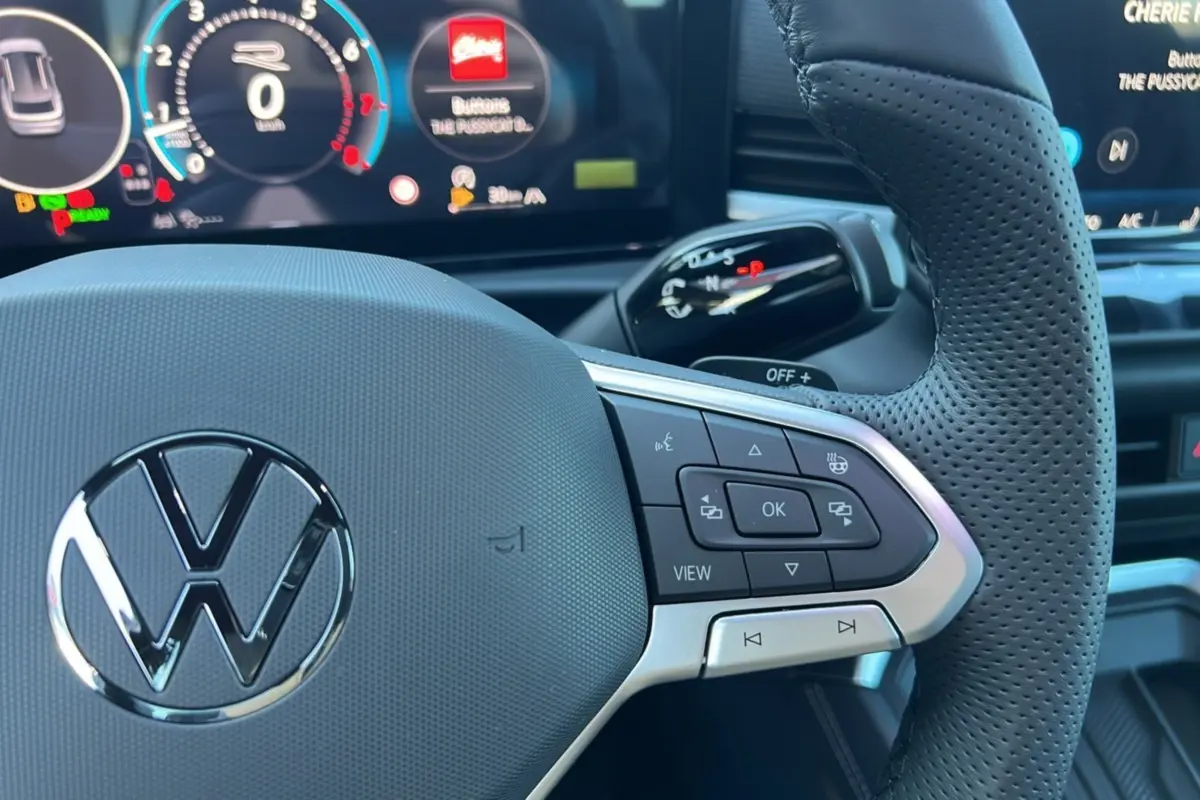 Gros plan sur le volant cuir perforé noir du Volkswagen T-Roc 2026 avec commandes multifonctions et tableau de bord digital.