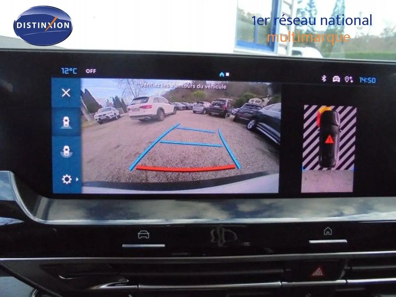 Vue de la caméra de recul du Citroën C5 X blanc métal, affichant les lignes de guidage sur un parking extérieur.