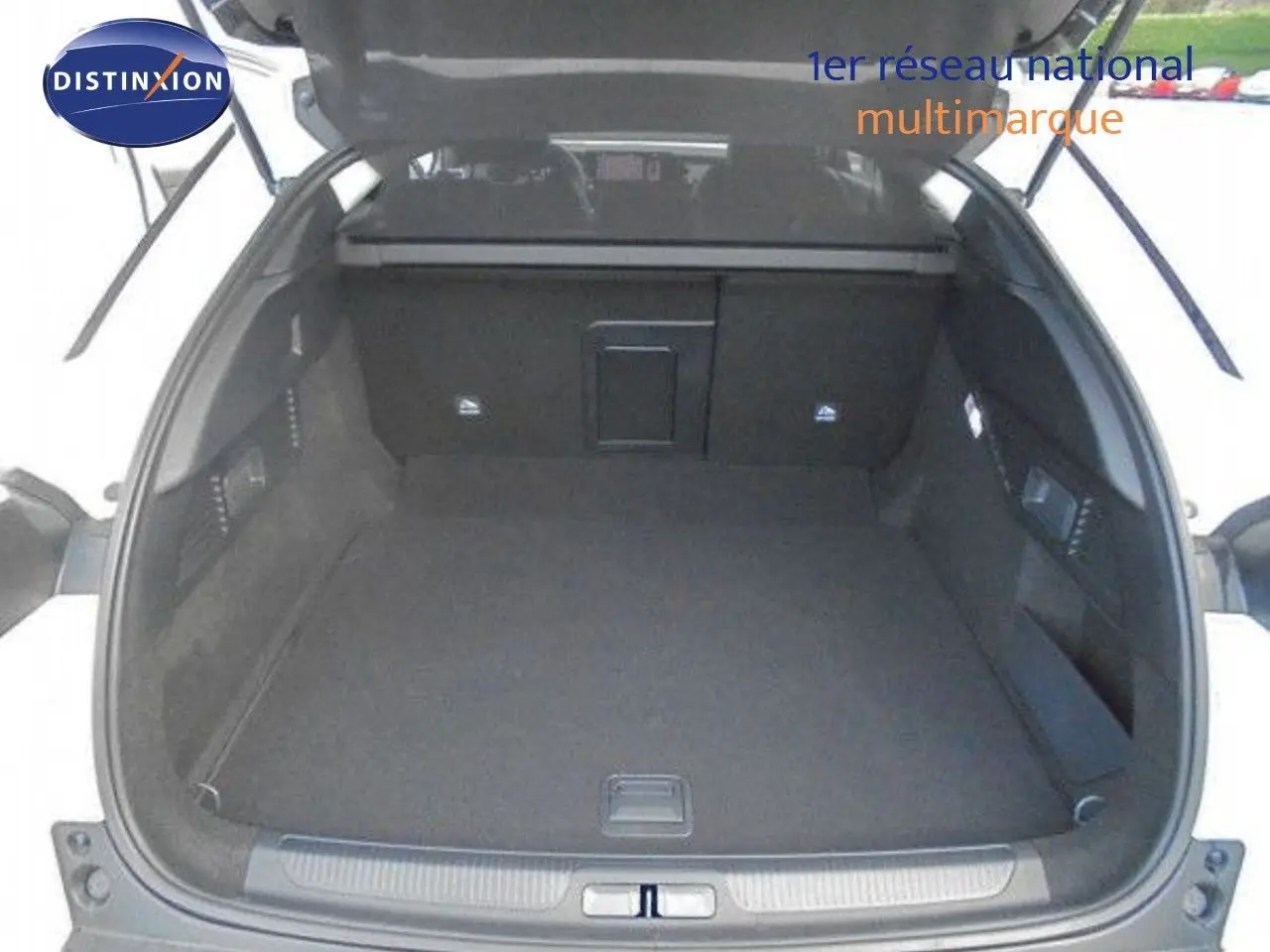 Coffre ouvert d'une Citroën C5 X blanc métal, vue arrière montrant l'espace de chargement vide et les finitions intérieures noires.