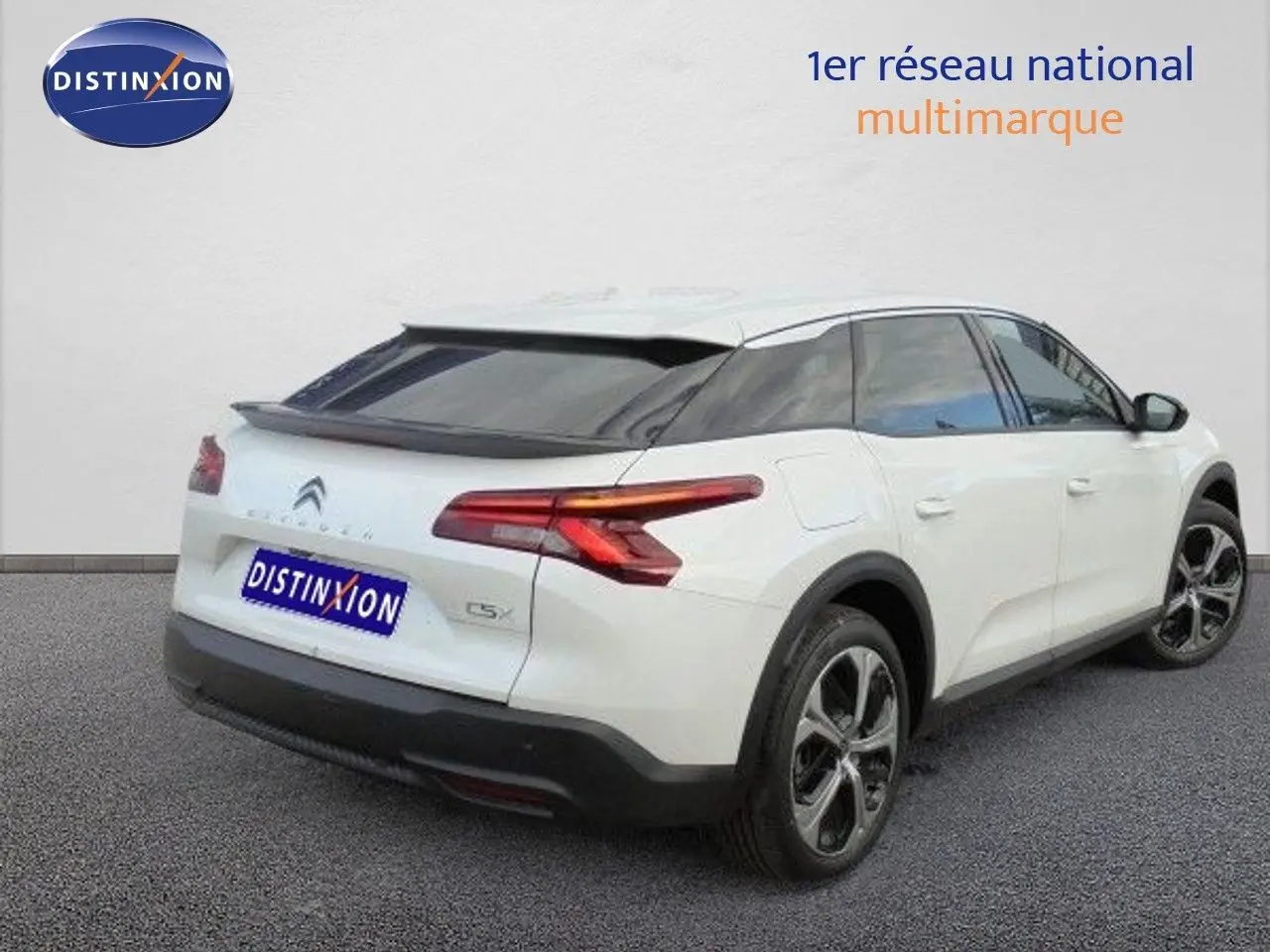 Vue 3/4 arrière droite d'une Citroën C5 X blanche métallisée avec feux LED et jantes bi-ton sur fond neutre.