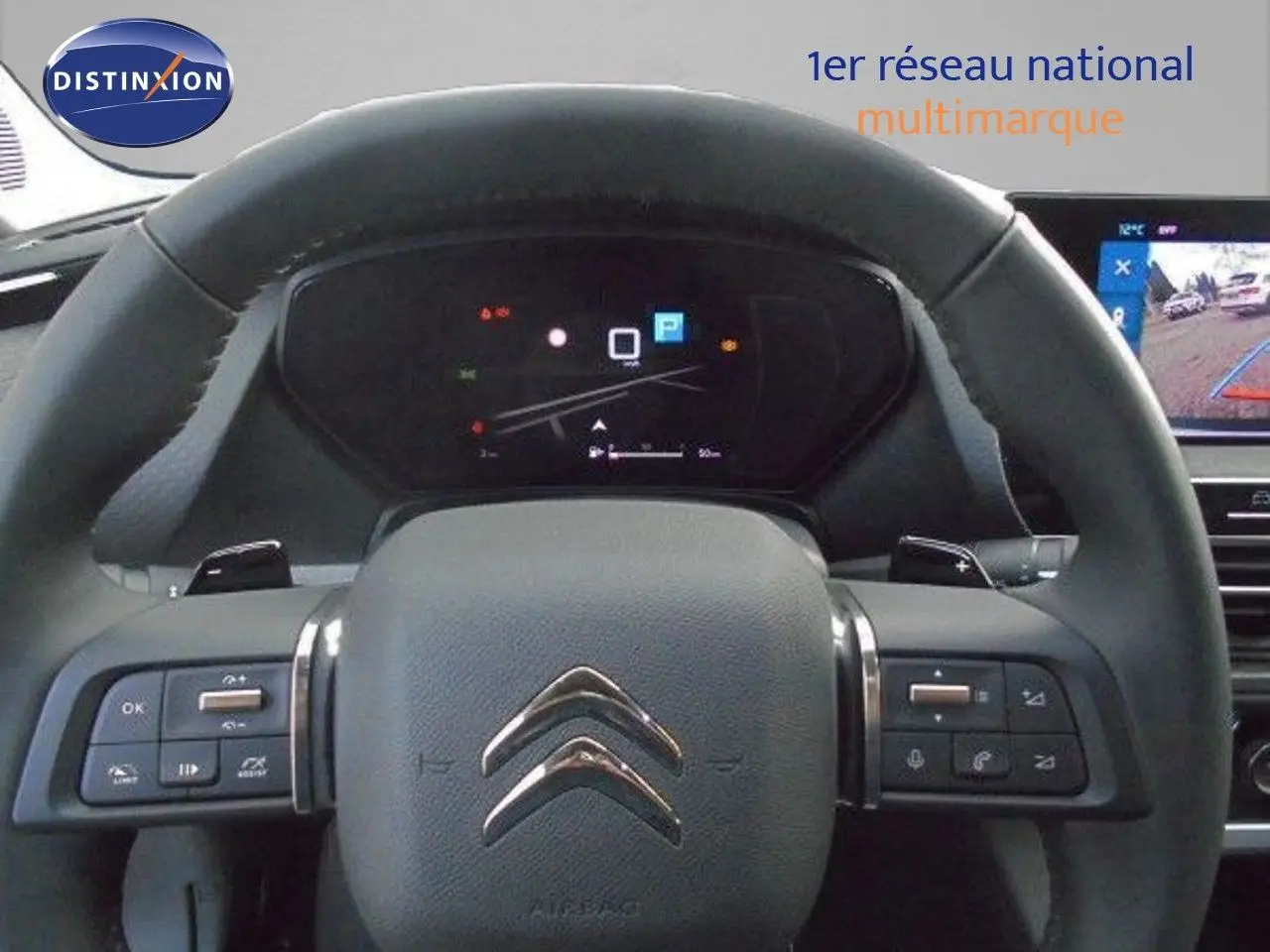 Volant en cuir noir de Citroën C5 X 2023 avec commandes intégrées et tableau de bord numérique en arrière-plan.