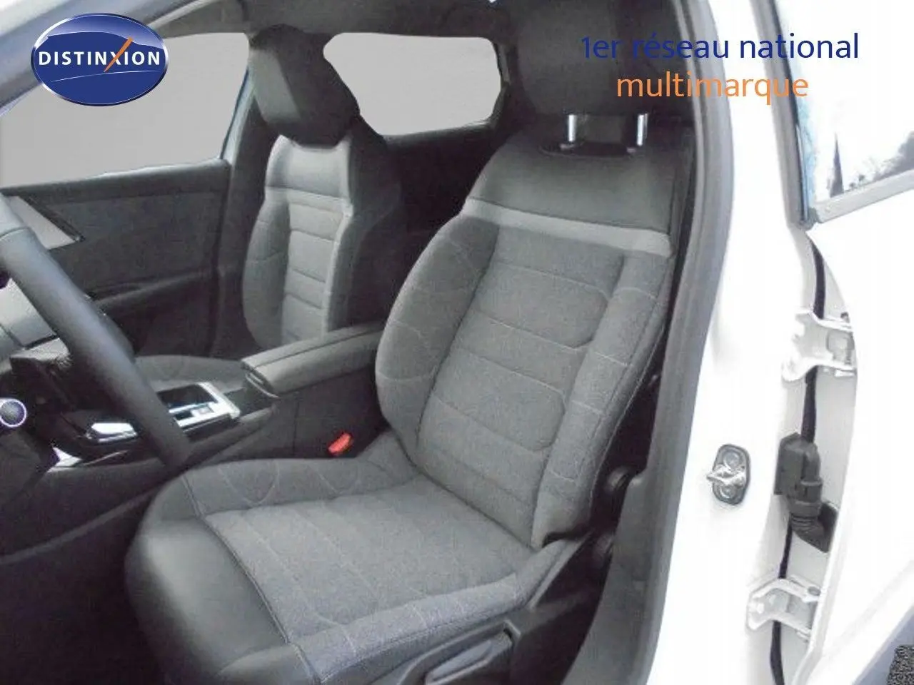 Vue intérieure côté conducteur d'une Citroën C5 X blanche métal, sièges tissu gris et cuir noir, console centrale visible.