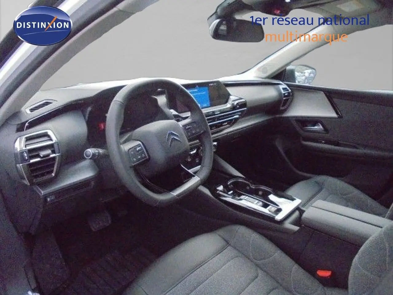 Vue intérieure côté conducteur de la Citroën C5 X 2023 avec tableau de bord moderne et sièges tissu gris foncé.