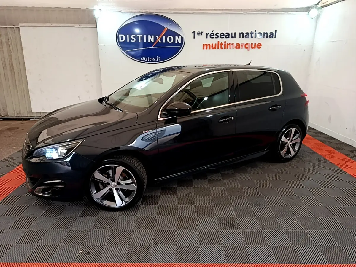 Peugeot 308 GT Line gris foncé vue de profil côté gauche dans un showroom avec éclairage intérieur.
