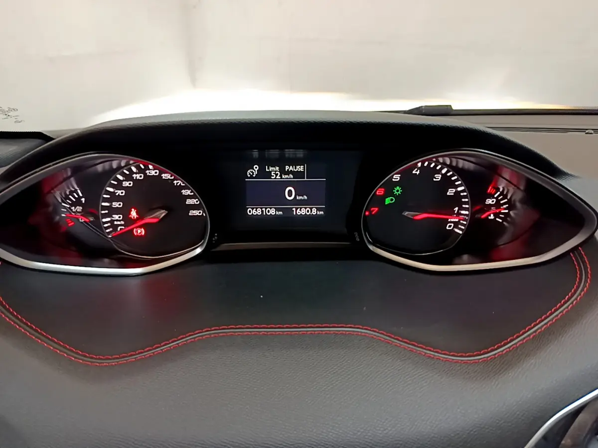 Tableau de bord de Peugeot 308 GT Line 2016, affichage numérique et compteurs analogiques avec surpiqûres rouges visibles.
