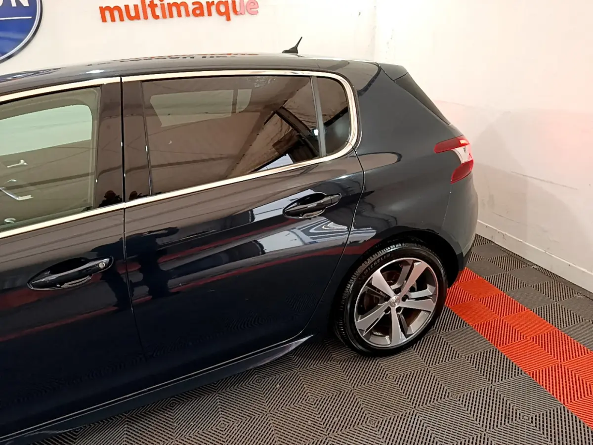 Vue côté droit arrière d'une Peugeot 308 gris foncé avec jantes alliage et feux arrière LED visibles.