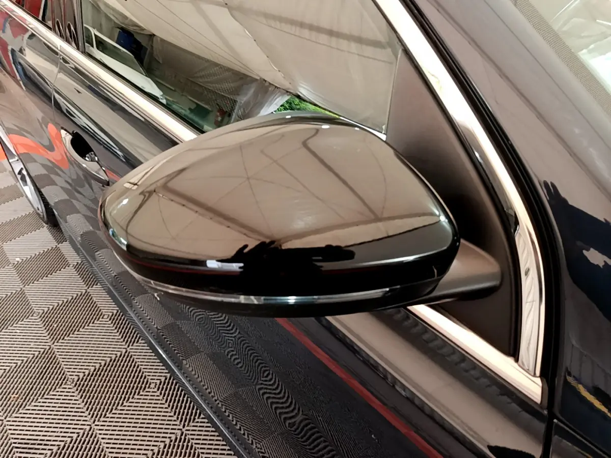 Rétroviseur côté gauche noir brillant de la Peugeot 308 gris foncé, vue rapprochée sur la portière avant.