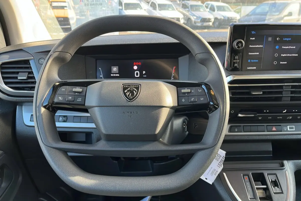 Vue intérieure centrée sur le volant multifonctions du Peugeot Traveller 2025 avec tableau de bord digital et écran tactile.