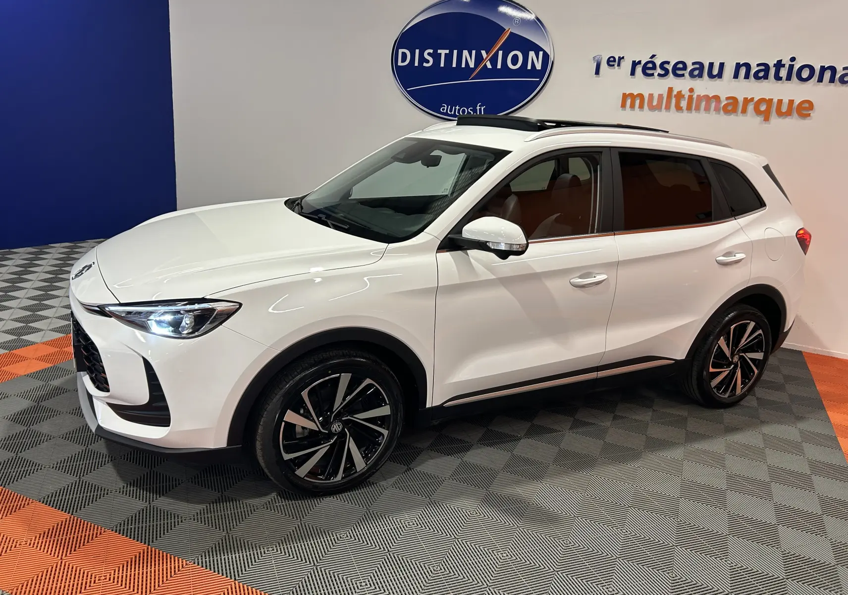 MG Motor ZS Hybrid+ 197 Luxury blanc Dover en 3/4 avant droit, avec toit panoramique ouvrant et jantes noires bicolores.