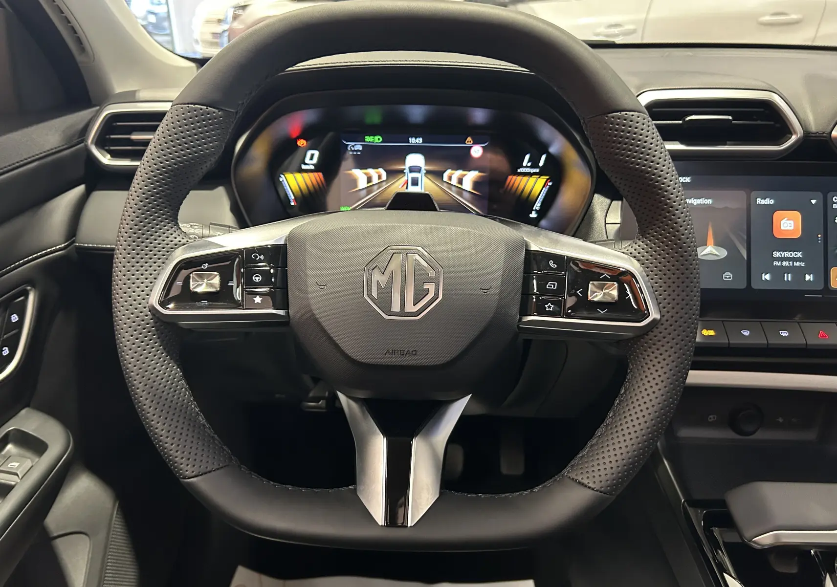 Vue intérieure centrée sur le volant noir perforé de la MG ZS Hybrid+ 2026 avec tableau de bord digital et écran tactile.