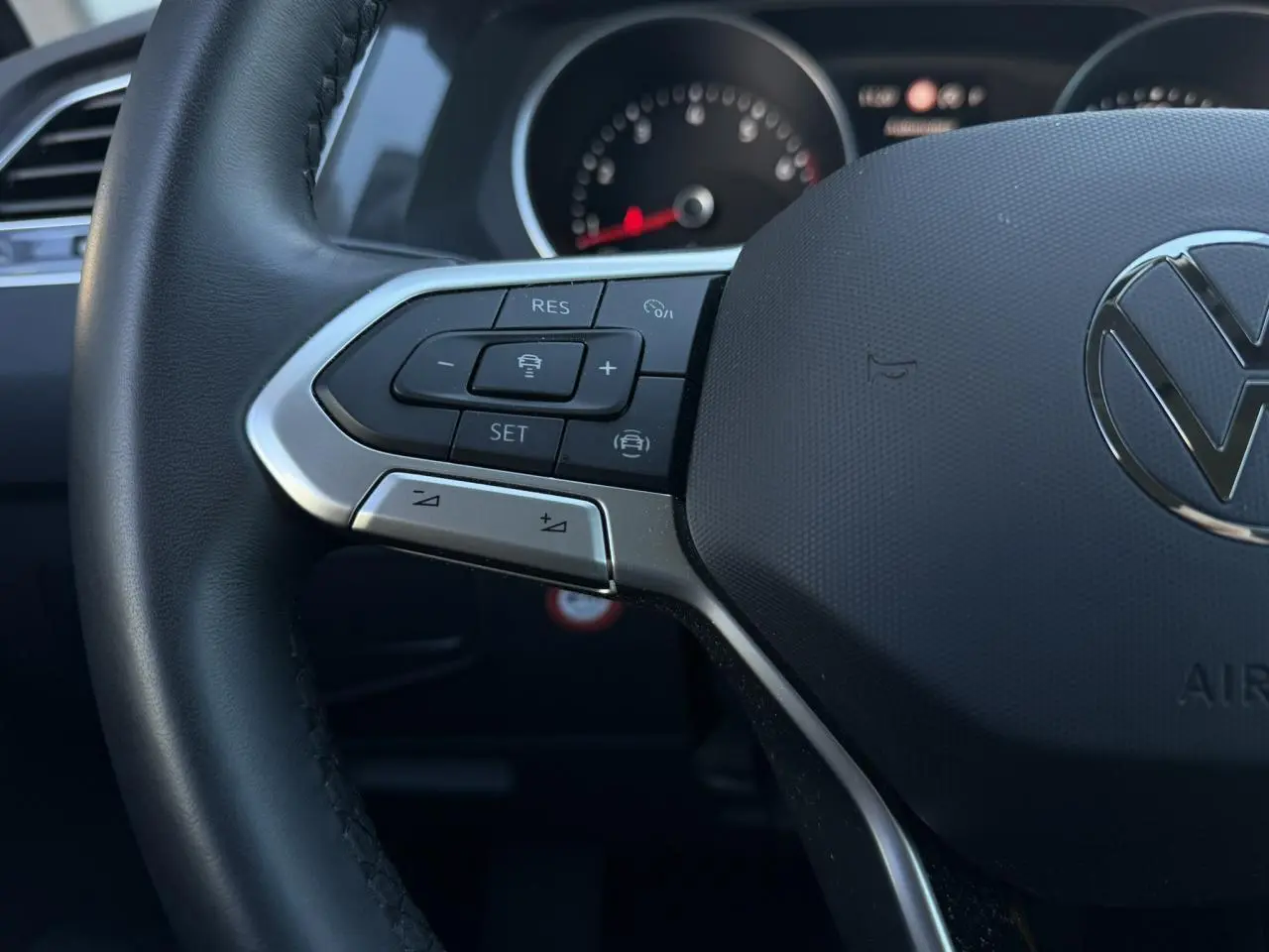 Gros plan sur le volant cuir multifonctions du Volkswagen Tiguan 2024 avec commandes de régulateur adaptatif.