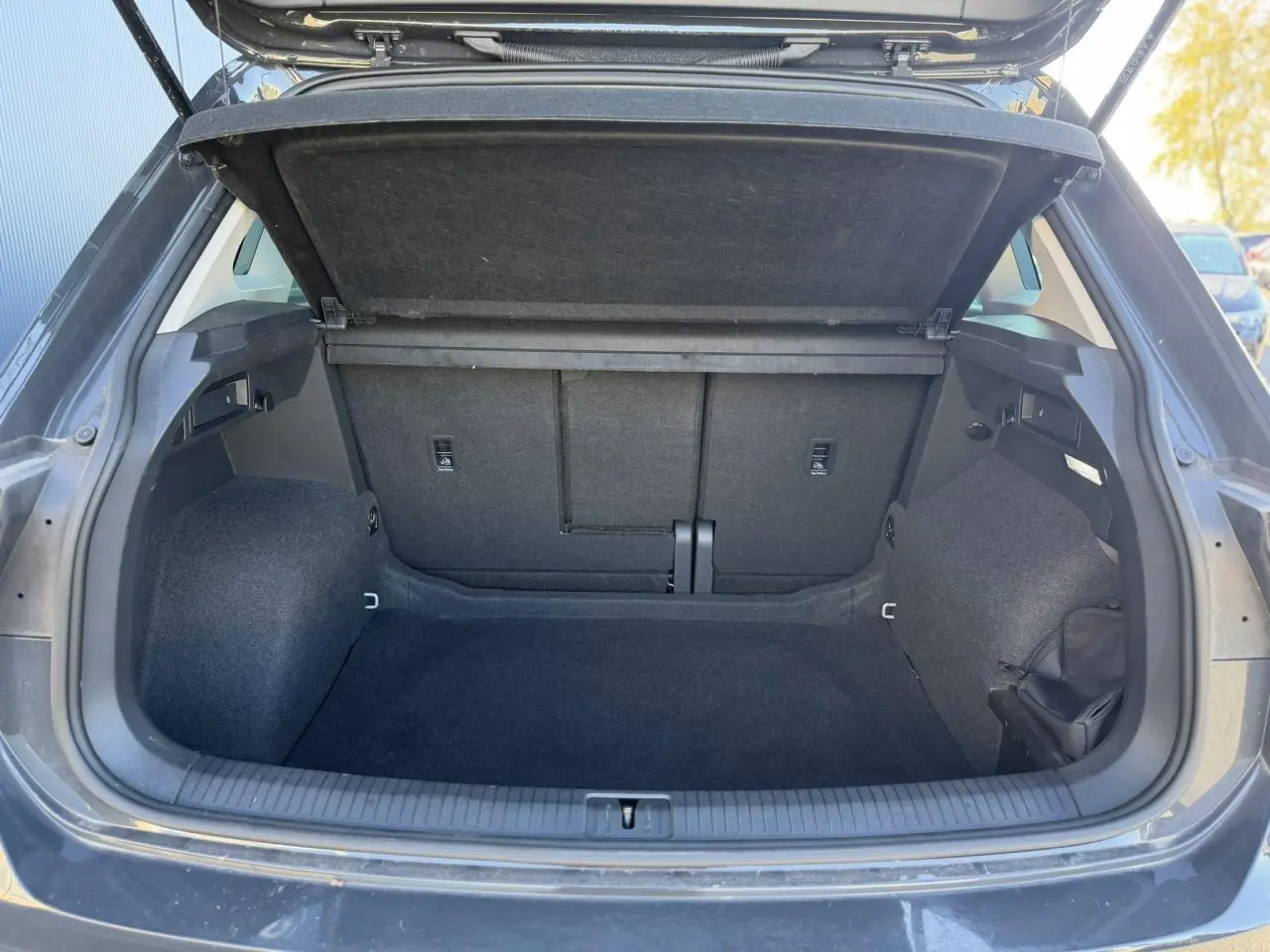 Coffre ouvert vu de l'arrière d'un Volkswagen Tiguan 2024 gris Urano, espace de chargement vide et propre.